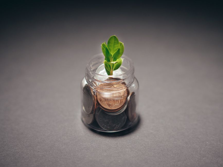 A close-up shot of a hand carefully placing a coin into a clear glass jar, symbolizing the simple, powerful act of building a small emergency fund for peace of mind.